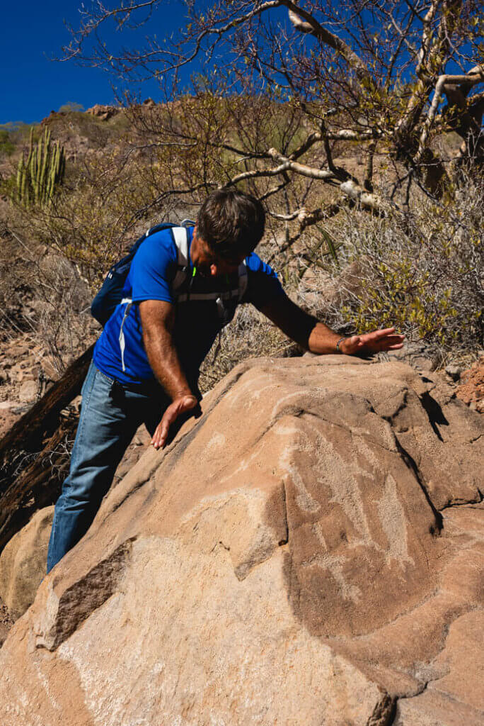 A guide of La Pingüica climbing on a rock to explain what he sees