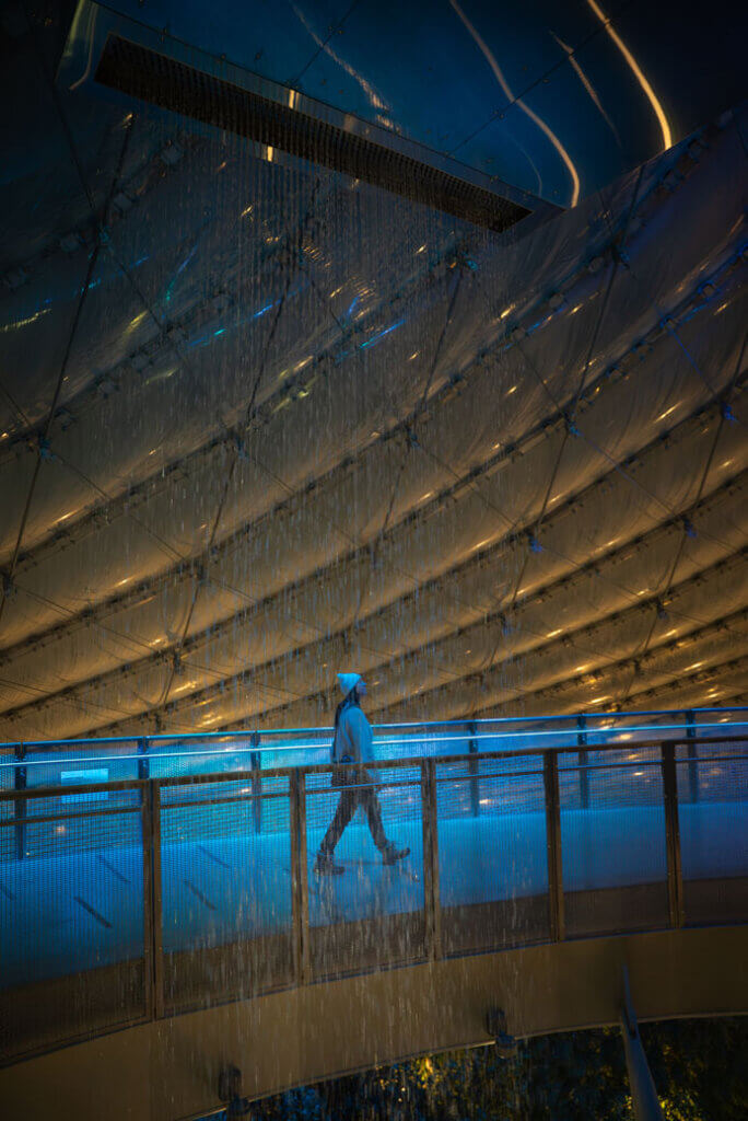 Megan walking under Canada's largest indoor waterfall in The Leaf in Winnipeg Manitoba