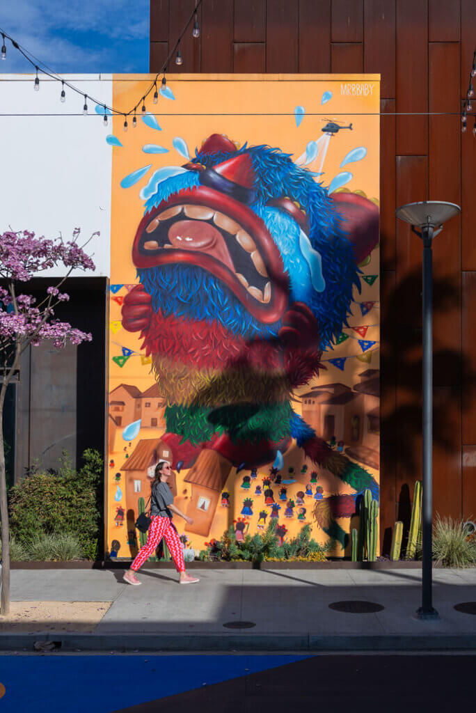 Megan walks in front of Mr.BBaby mural at The Promenade in Long Beach