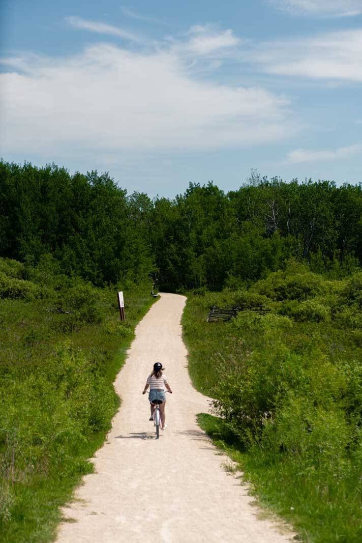 Megan riding away on a bike at Fort Whyte Alive in Winnipeg