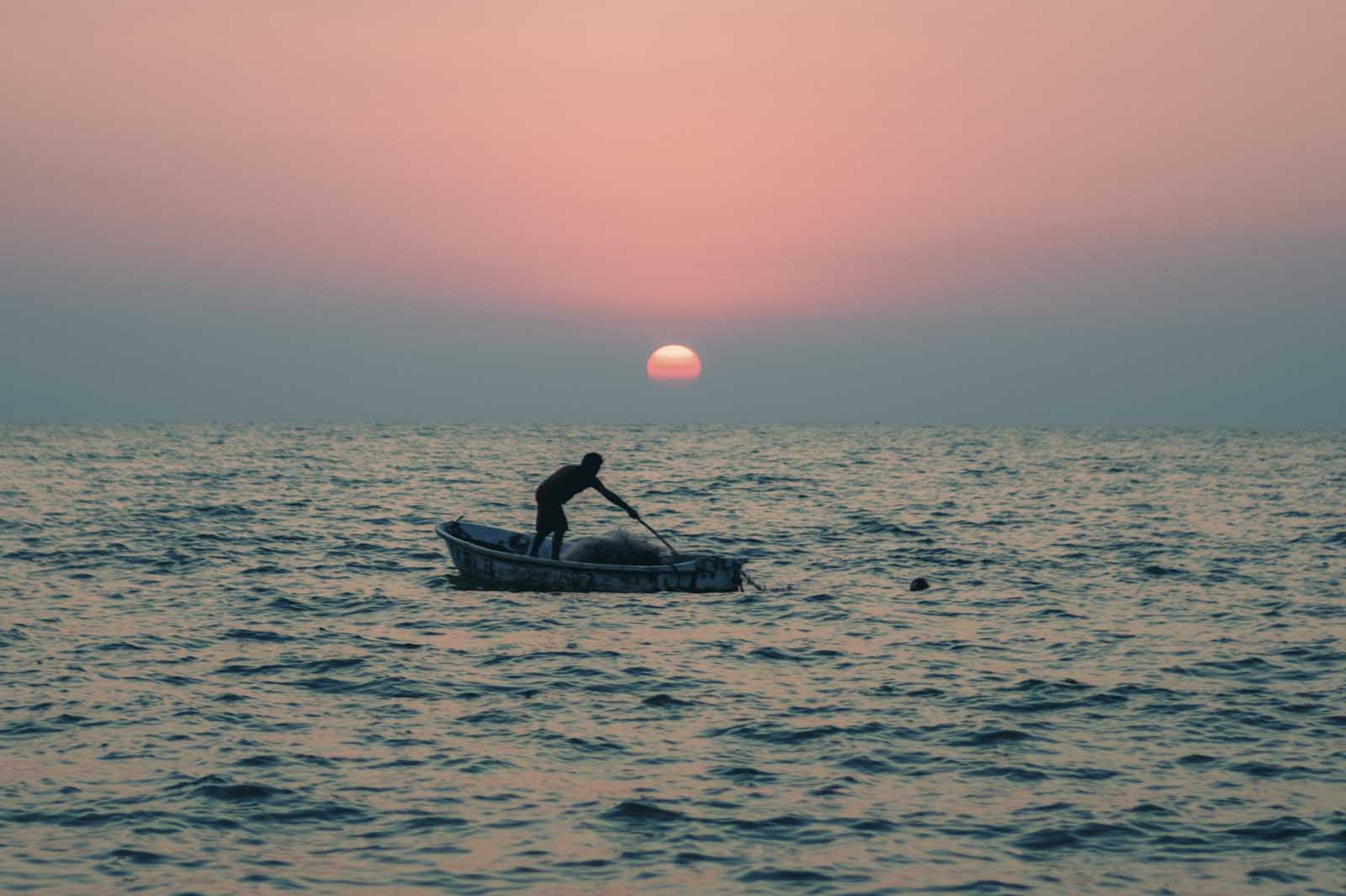 A fisherman in a boat as the sun sets in Celestún