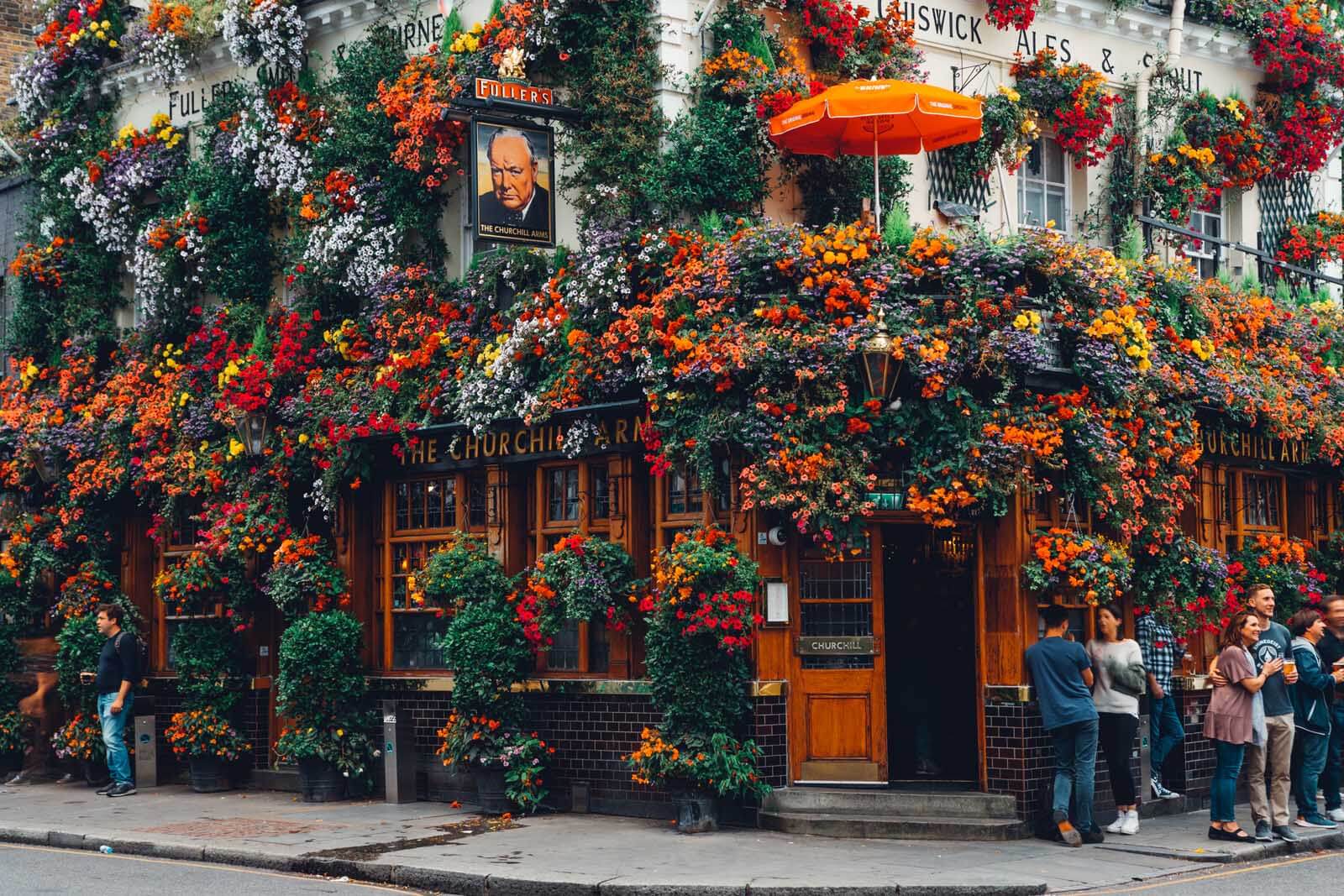 people gathering around the flowery Churchill Arms Bar in London