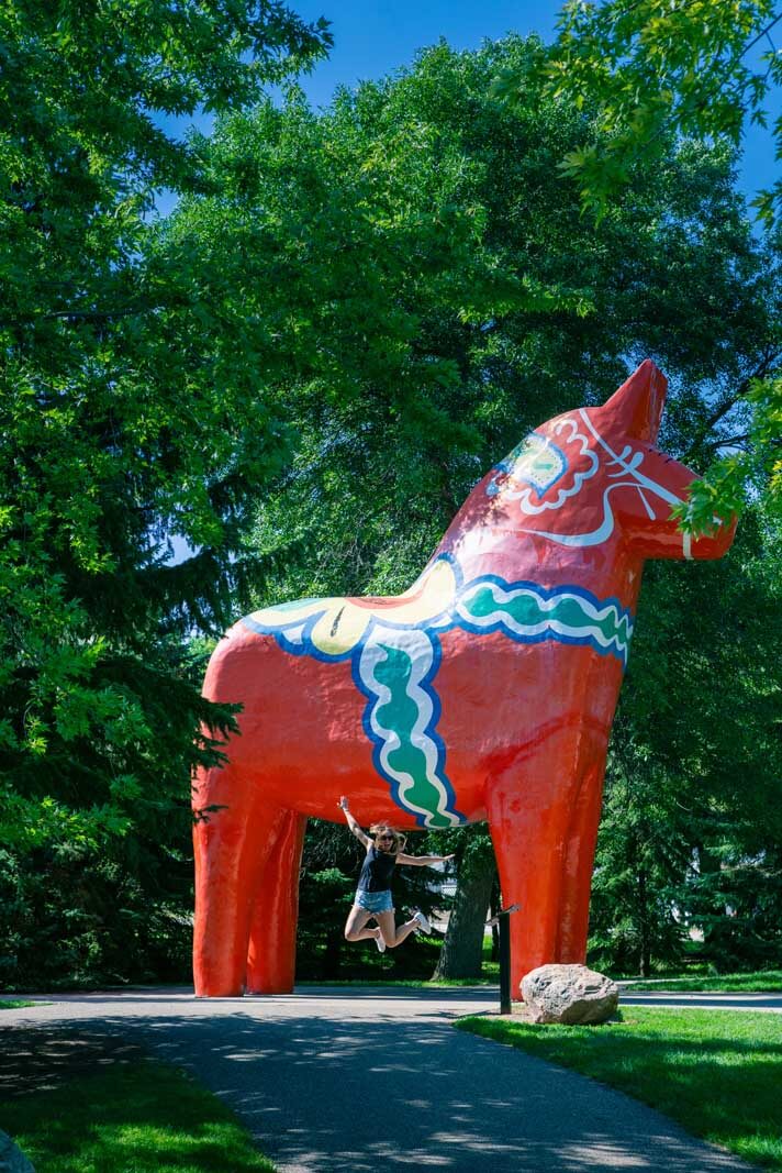 Megan jumping at Large Swedish Dala Horse at the Scandinavian Heritage Park in Minot North Dakota