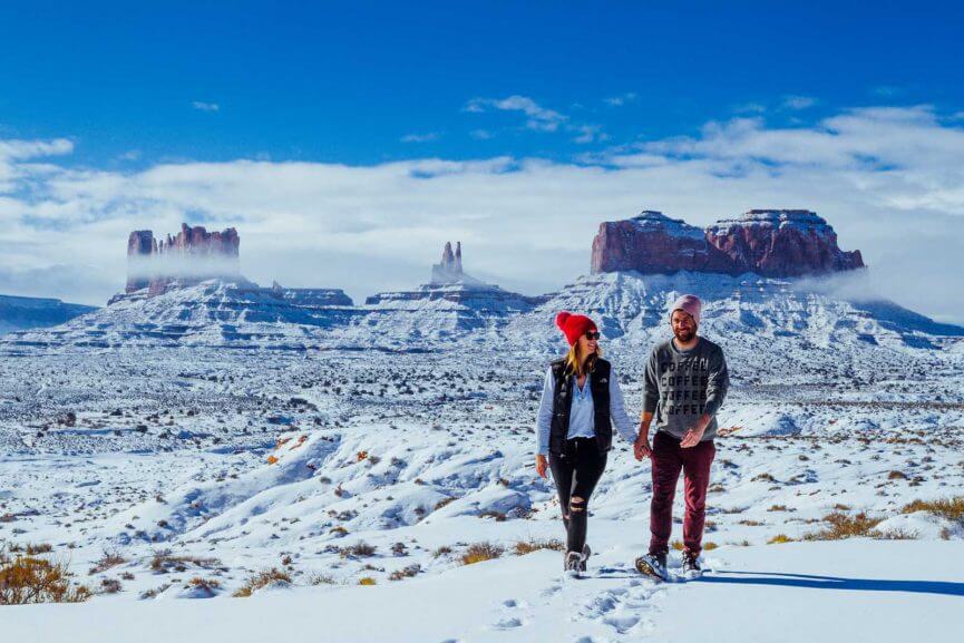 Megan and Scott walking in snow with Monument Valley in the background