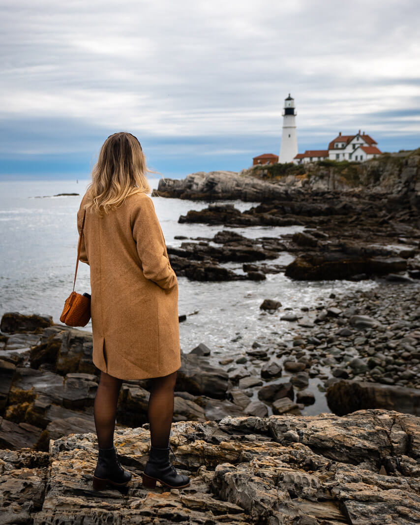 Megan enjoying the view of Portland Head Lighthouse from the rocks along Fort Williams Park in Maine