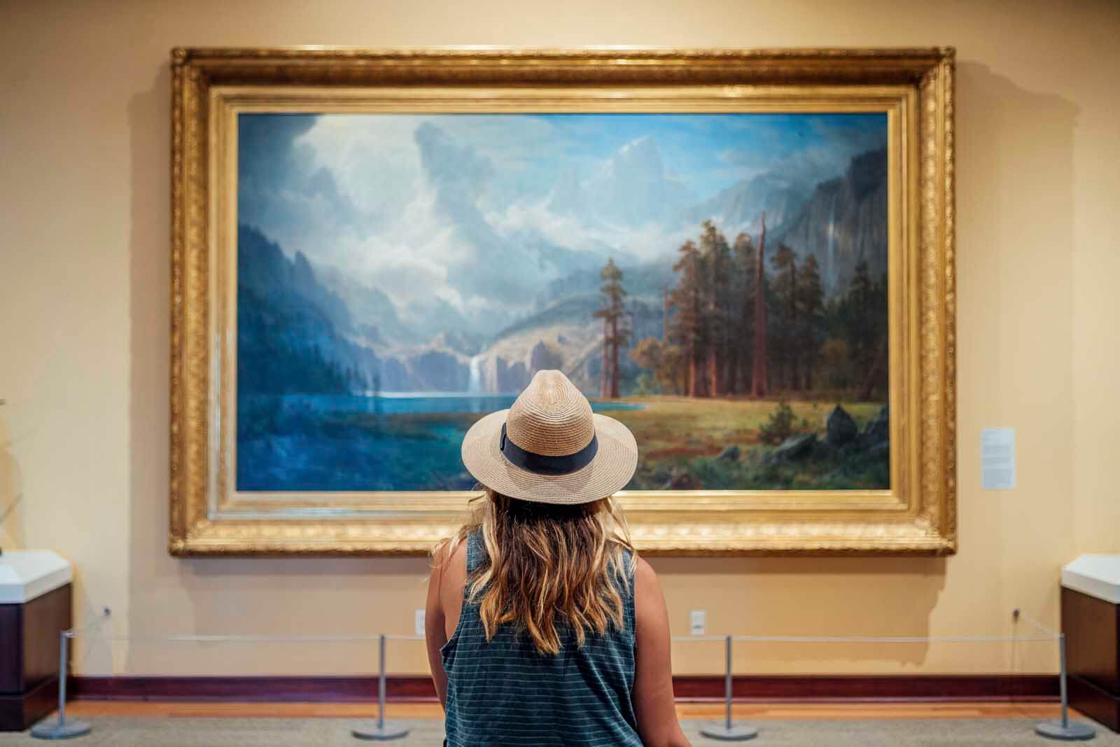 Megan sitting and looking at a landscape painting in Rockwell Museum in Corning