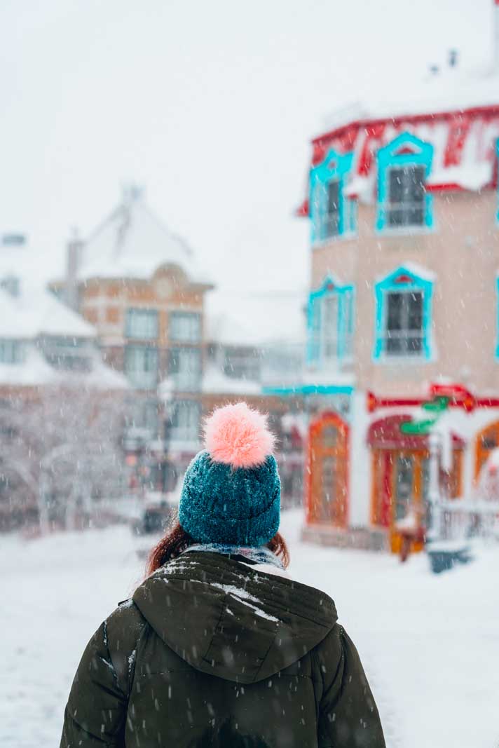 Megan looking at the village in Mont Tremblant in winter during snowfall