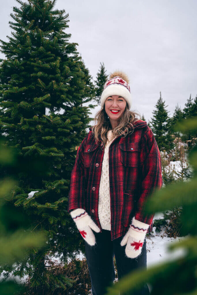Megan next to some Christmas treest as the Balsam Fir Christmas Tree Capital of the World in New Ross Nova Scotia