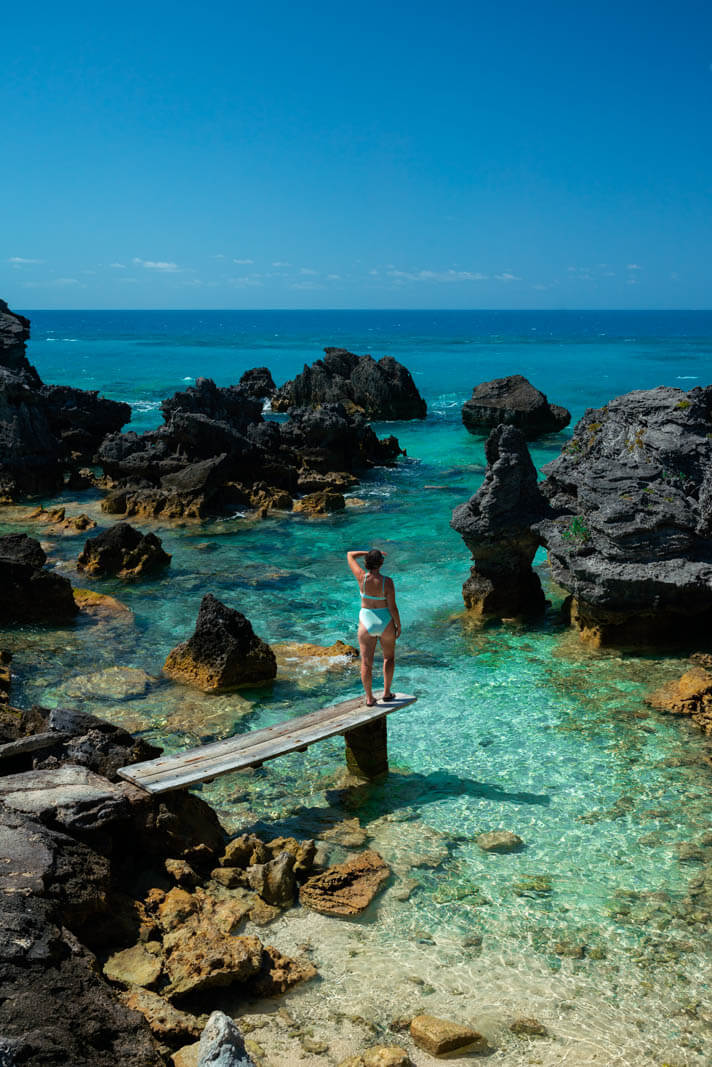 Megan on the plank looking out at tbe blue water at Tobacco Bay Beach in Bermuda