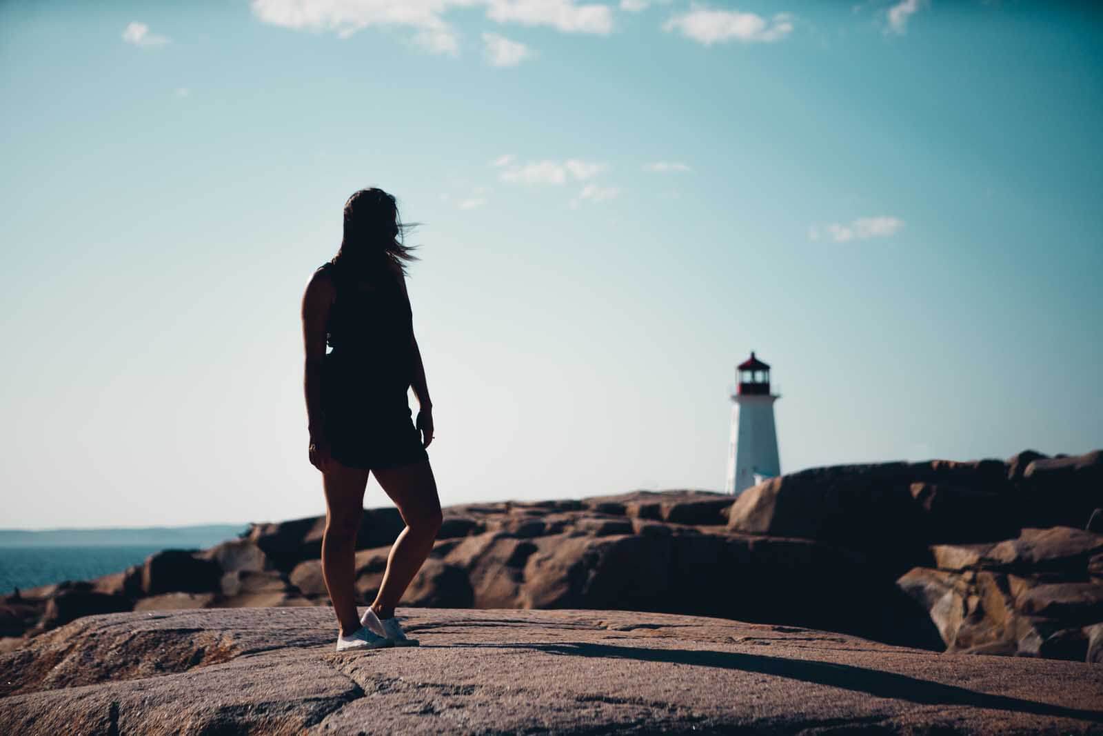 Megan at Peggy's Cover on the rocks looking at the lighthouse