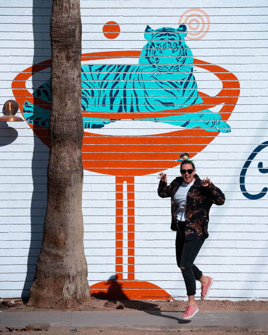 Megan posing outside of the Churchill with a mural in downtown Phoenix