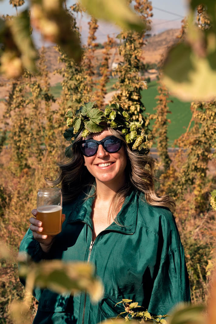 Megan surrounded by hops with a hop crown and beer at Cowiche Brewing Company in Yakima Valley Washington