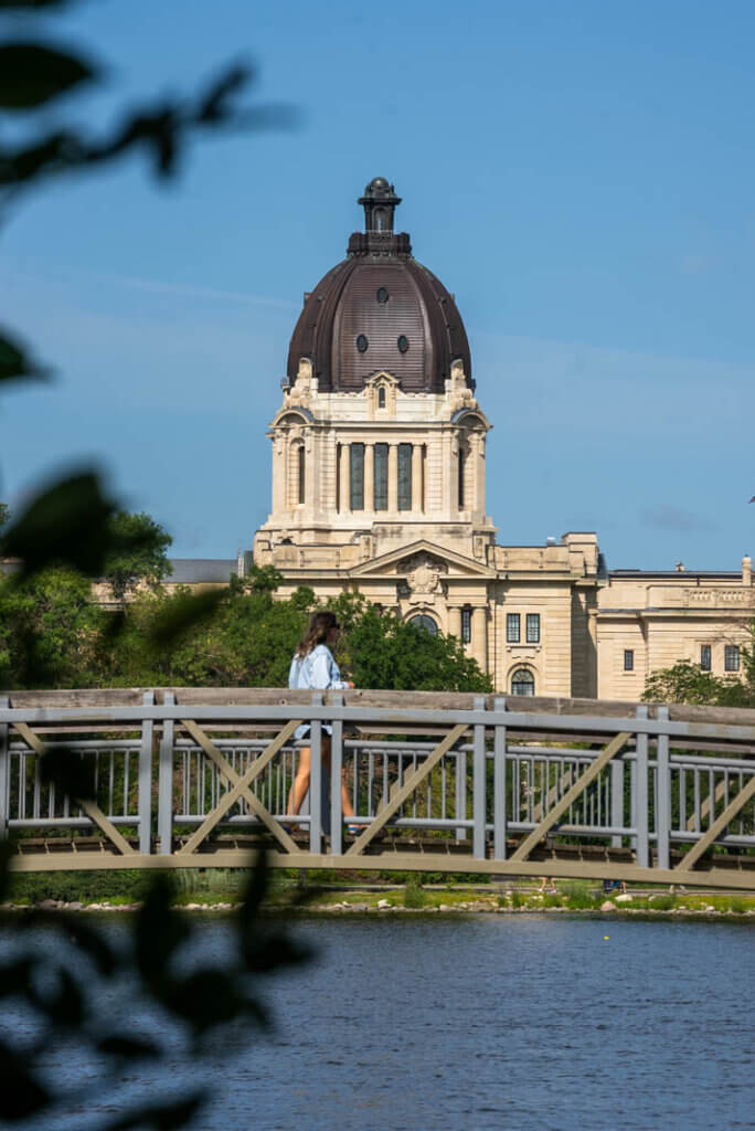 Megan walking through Wascana Park with a view of the Legislative Building in the background in Regina Saskatchewan