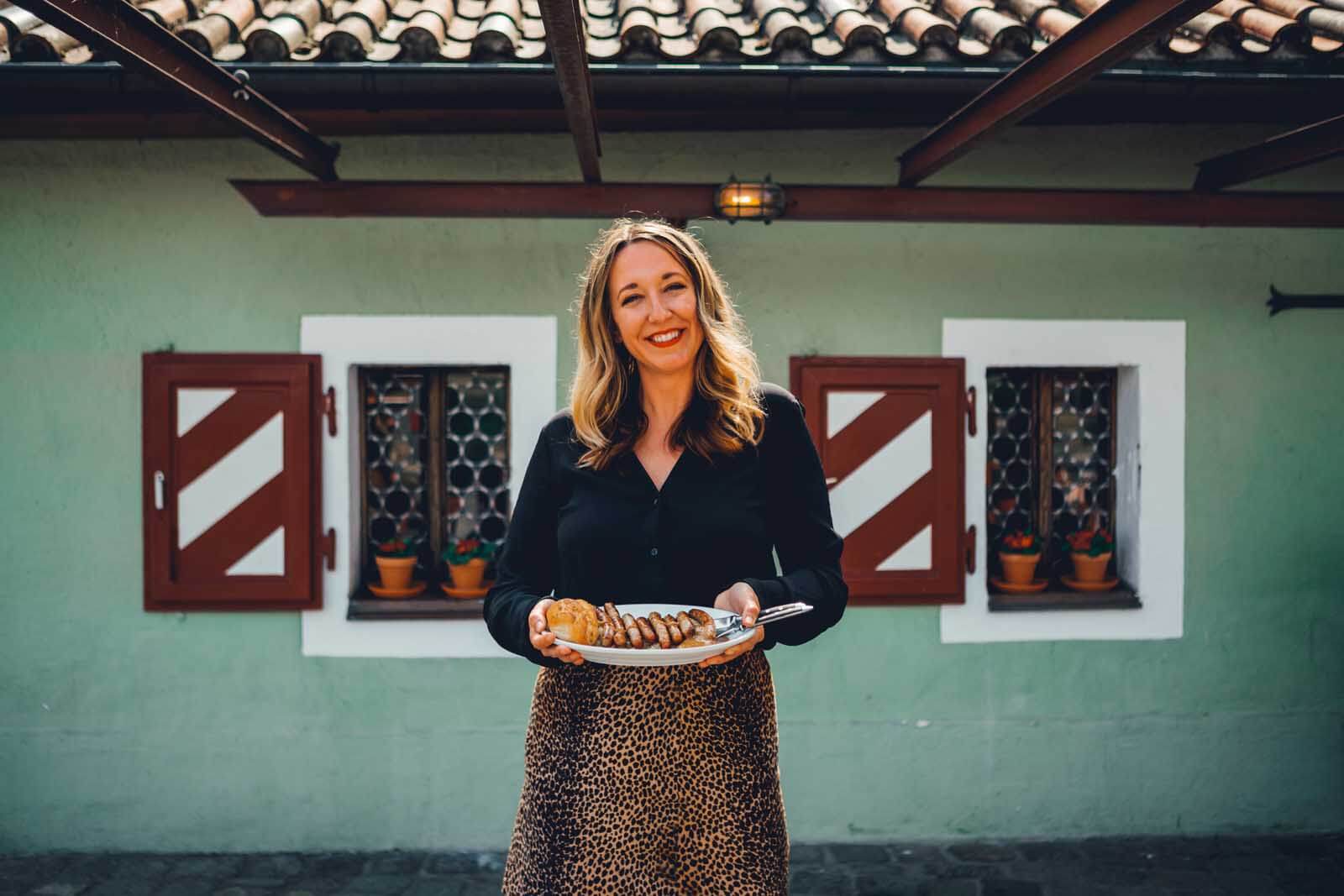 Megan holding a plate of sausages at the worlds oldest continuous running restaurant in the world