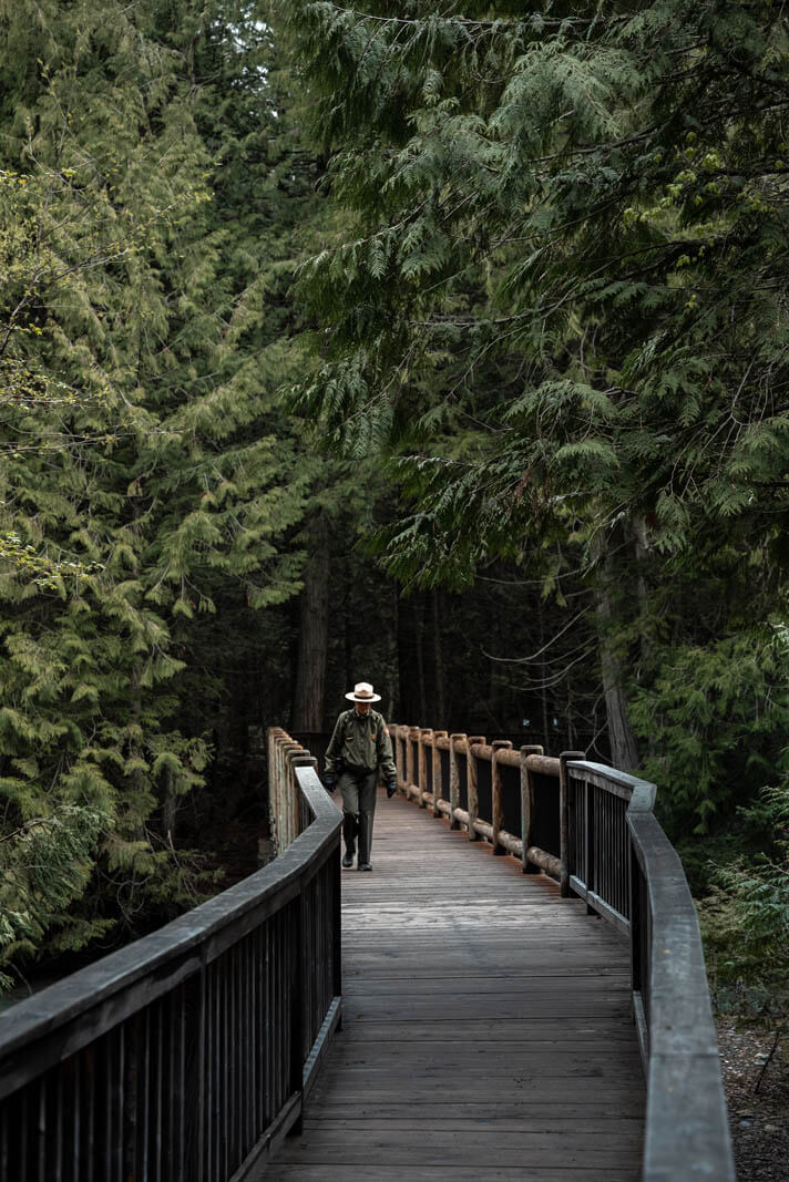 Park Ranger walking along the Trail of the Cedars in Glacier National Park in Montana