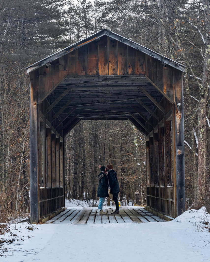 a kiss under Island Properties Covered Bridge in Peru Vermont