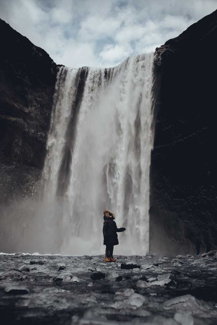 child at the base of skogafoss waterfall