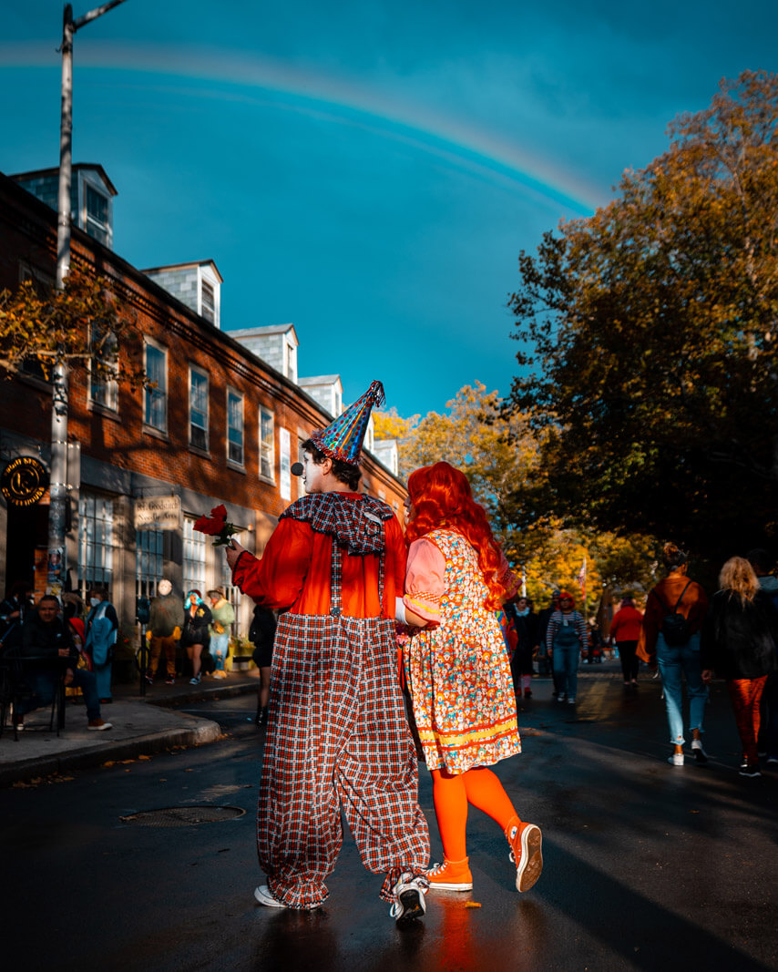 clown couple walking through Salem Massachusetts on Halloween with a rainbow