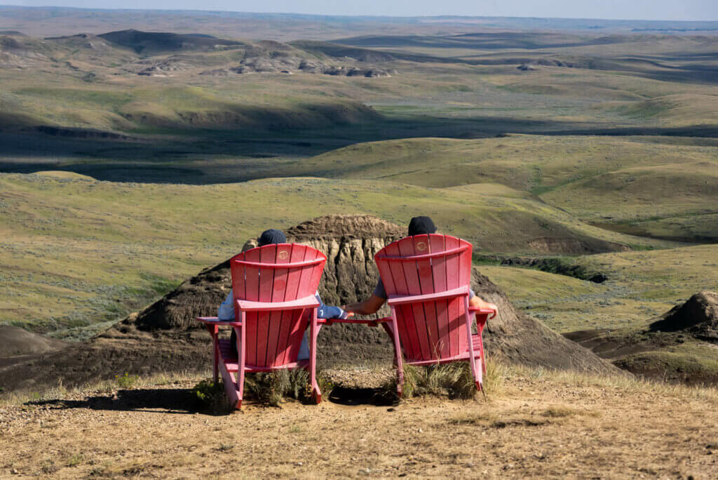 couple enjoying the Parks Canada red chairs at Ta Sunka Watogla along the Badlands Parkway in Grasslands National Park East Block in Saskatchewan