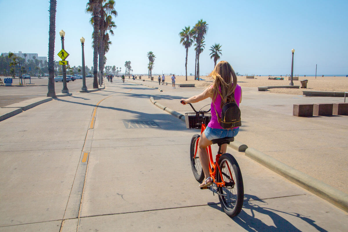 girl-biking-down-the-Venice-Beach-Boardwalk-in-Venice-Beach-Los-Angeles-California