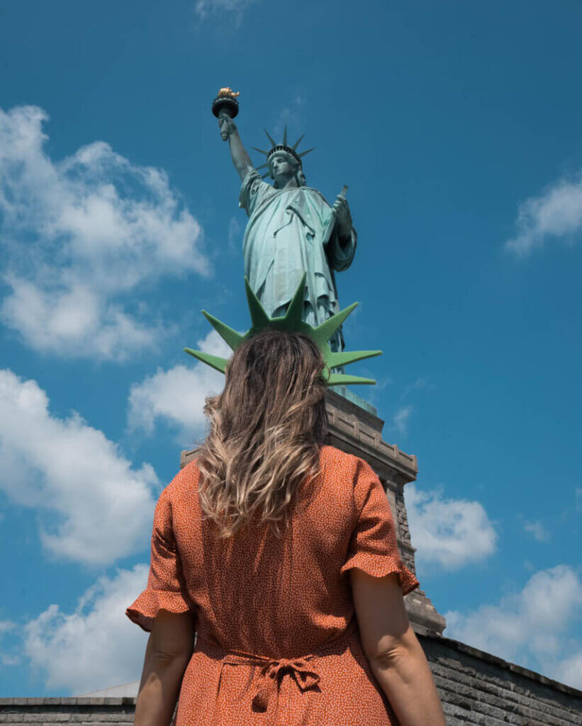 looking at the Statue of Liberty on Liberty Island wearing a lady liberty crown in NYC