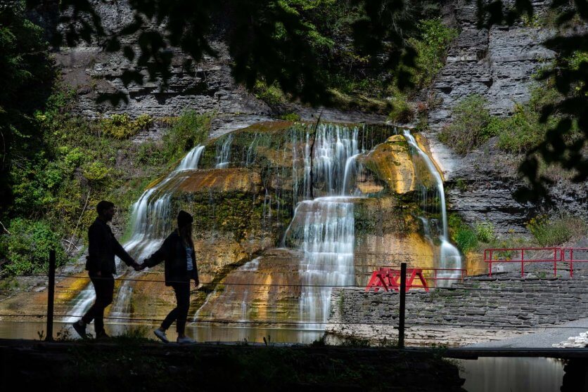 megan and scott walking in front of enfield falls at robert treman state park in ithaca ny