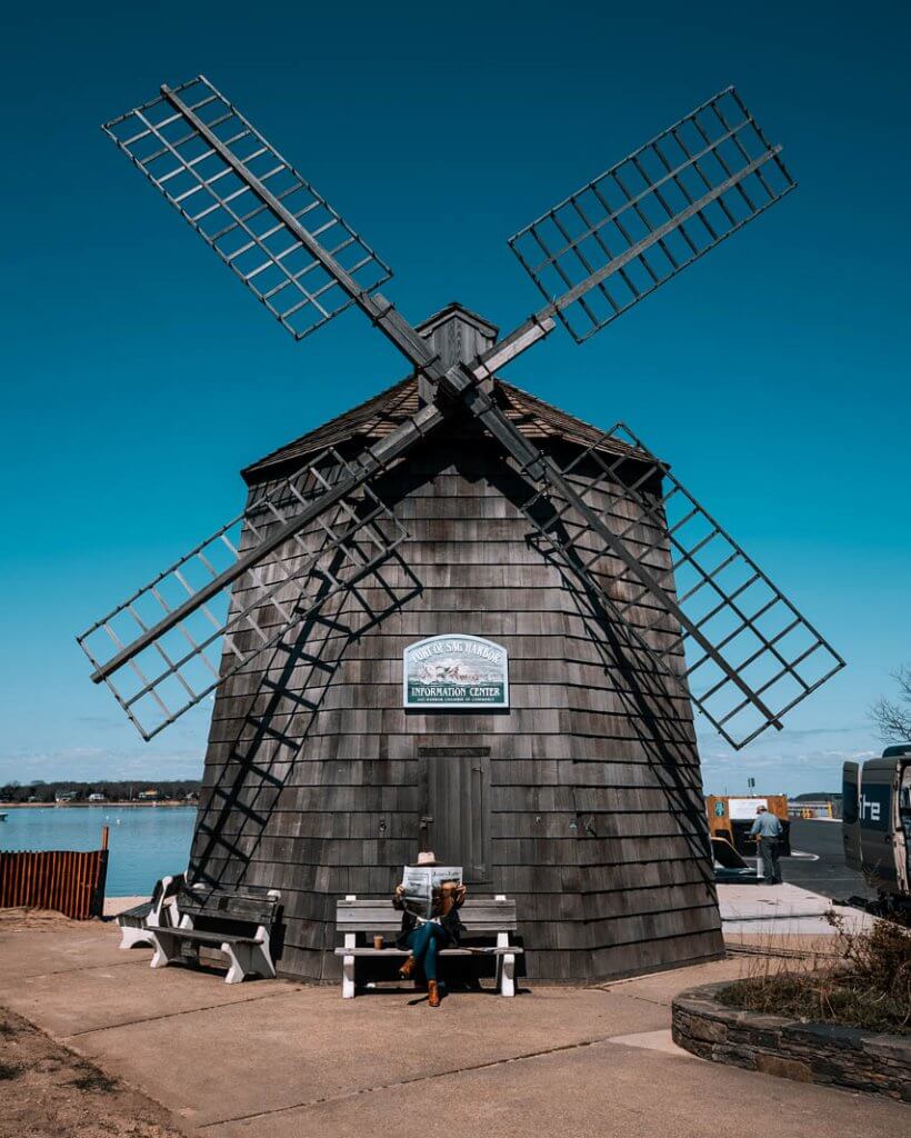 megan reading a newspaper under the windmill in Sag Harbor Hamptons New York
