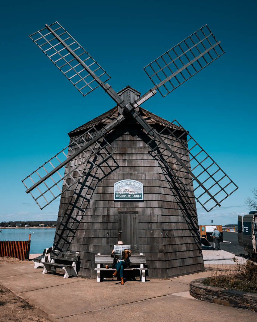 megan reading a newspaper under the windmill in Sag Harbor Hamptons New York