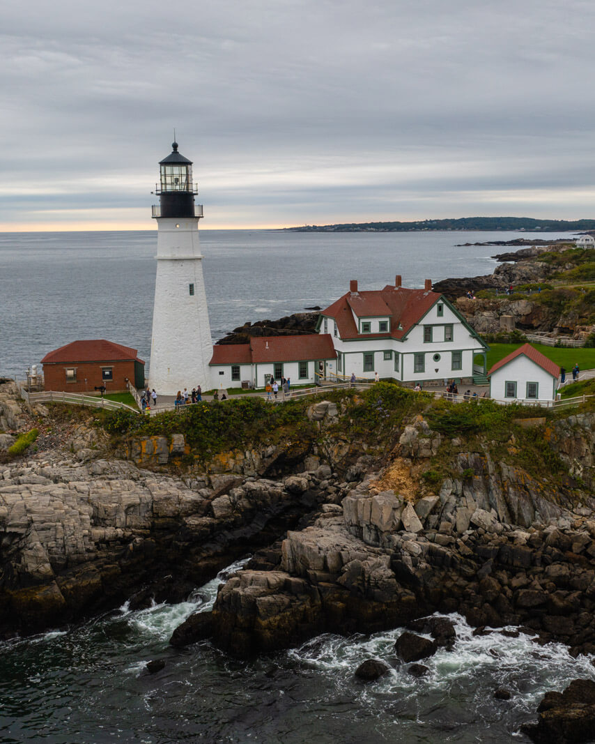 rocky coastline and aerial view of Portland Head Lighthouse in Maine overlooking Casco Bay