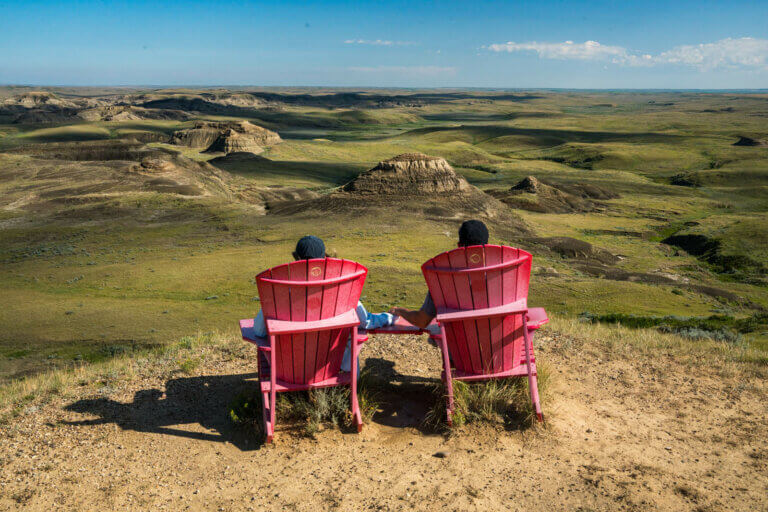 sitting at the Parks Canada red adirondack chairs at Ta Sunka Watogla in Grasslands National Park East Block along Badlands Parkway in Saskatchewan