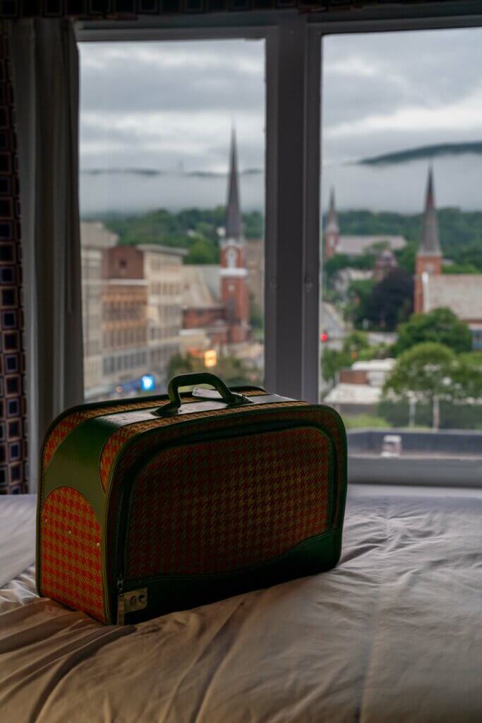 view of luggage on bed in Hotel Downstreet with the view of town of North Adams in the window in the Berkshires
