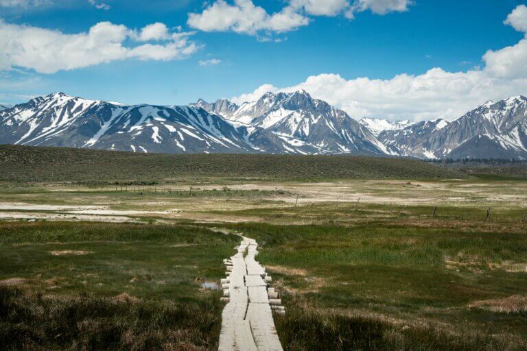 view of the snowy mountains and walkway to Hilltop Hot Spring in Mammoth Lakes California