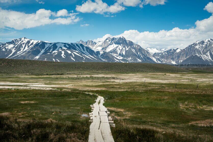 view of the snowy mountains and walkway to Hilltop Hot Spring in Mammoth Lakes California